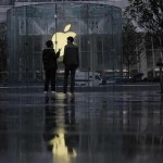 Two men stand in front of an Apple logo outside an Apple store in Shanghai